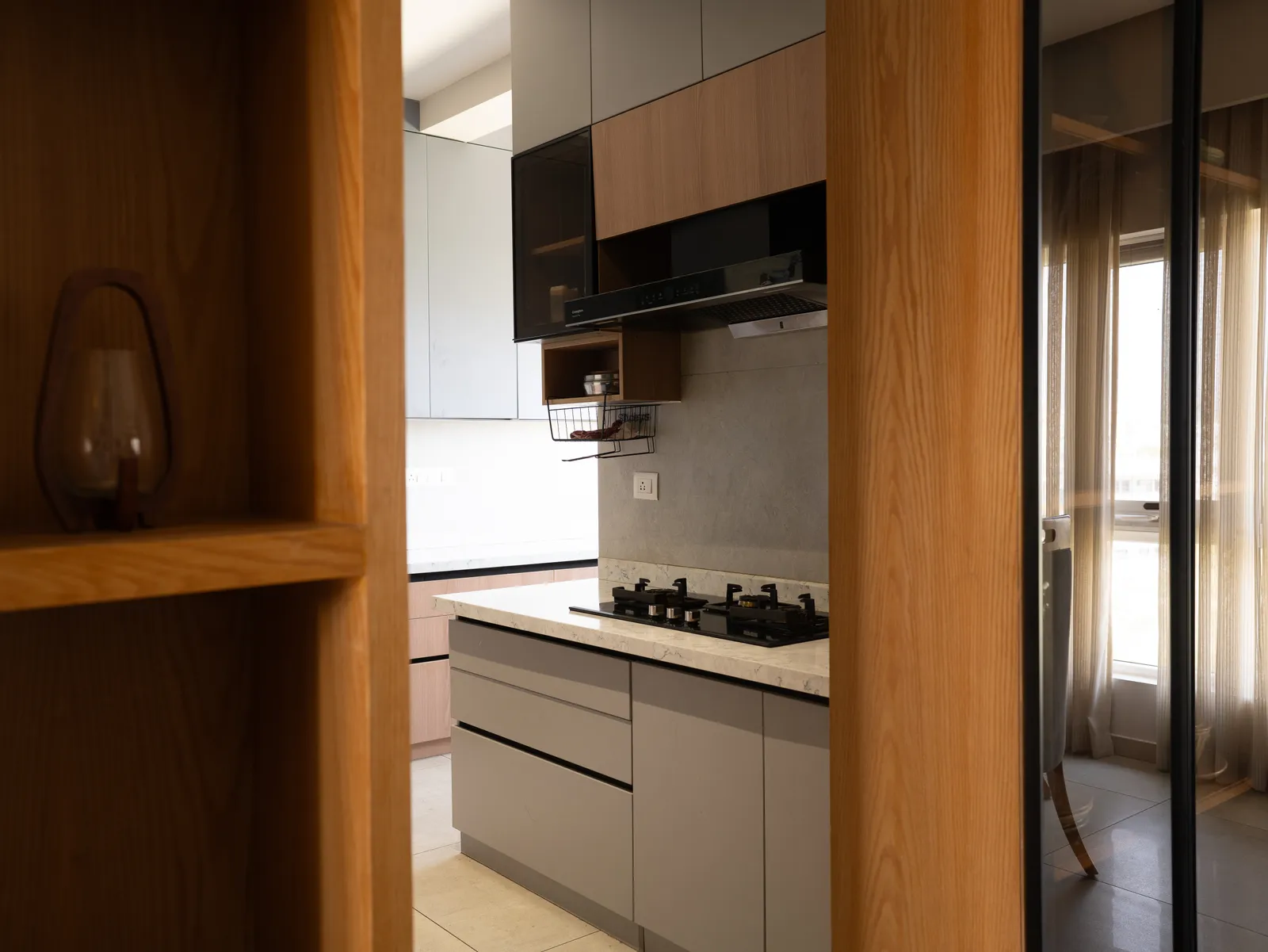 Kitchen seen through an oak-framed glass sliding door — Amlan's Residence